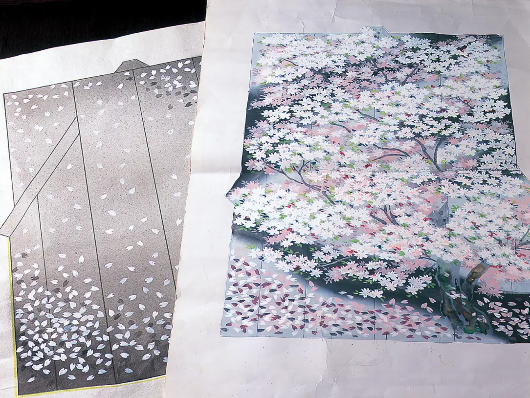 左側にモノトーンのシックな背景に舞い散る桜の花びらが描かれた着物のデザイン画と、右側に満開の桜の木から無数の花びらが美しく吹き荒れる様子が色鮮やかに描かれた、2枚の着物のテキスタイル・デザイン図案(絵羽模様)