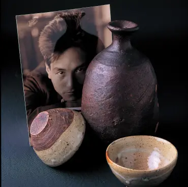 モノクロ写真の前に、味わい深い黒茶色の備前焼の徳利と、白い釉薬が流れる2つのぐい呑(酒器)を並べて配置した画像